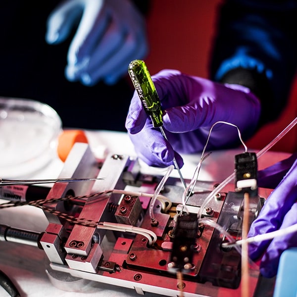 gloved hands working on a circuit board