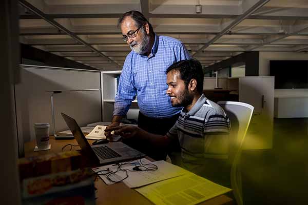 professor and student researcher at computer discussing
