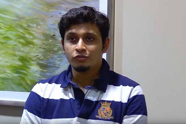 student in striped blue and white shirt speaking to the video camera