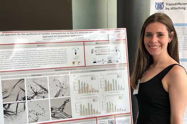 student smiling next to research poster on display