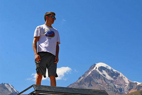 student standing high on bridge with blue sky in background