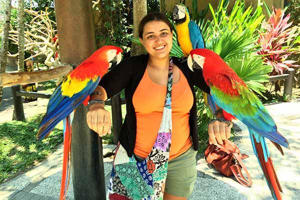student with parrots on each arm smiling