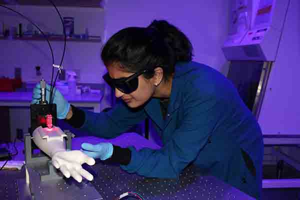 alumna works in the lab at her job working on a mechanical hand