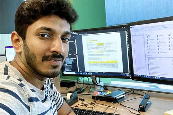 alumnus working at his job in front of double monitors