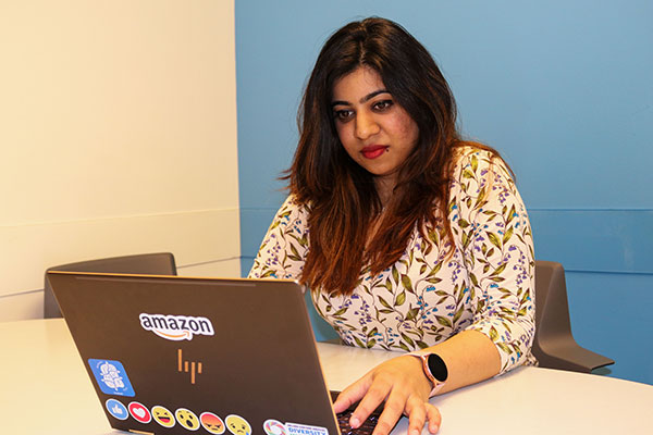 student working on computer with Amazon stick on the back of laptop