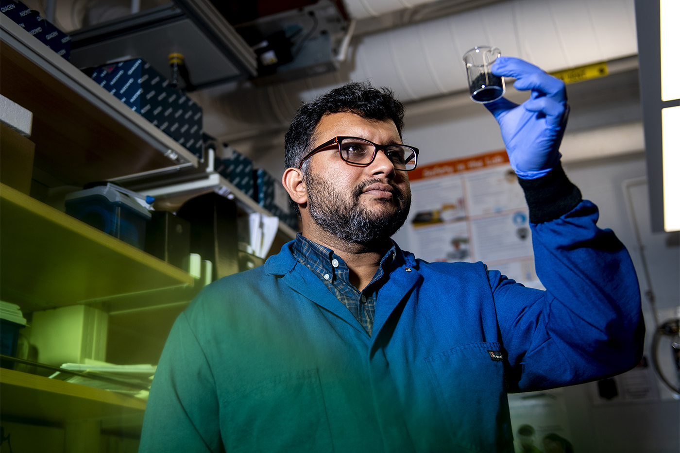 Ameet Pinto in environmental engineering lab holding up liquid