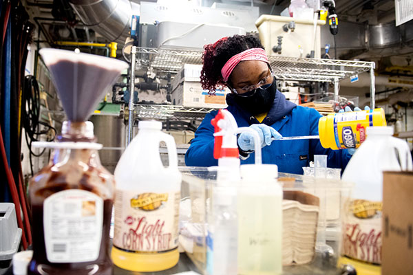 student working in chemical engineering lab pouring a chemical