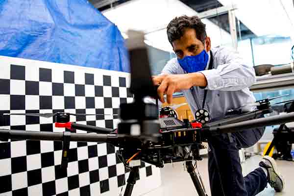 professor kneeling working on drone in lab