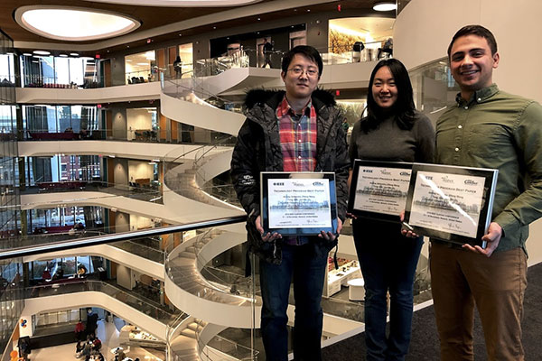 three students show their framed awards