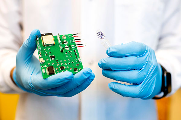 person in lab coat holding sensor