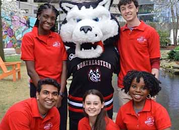 five students and a person dressed up as a husky mascot smiling