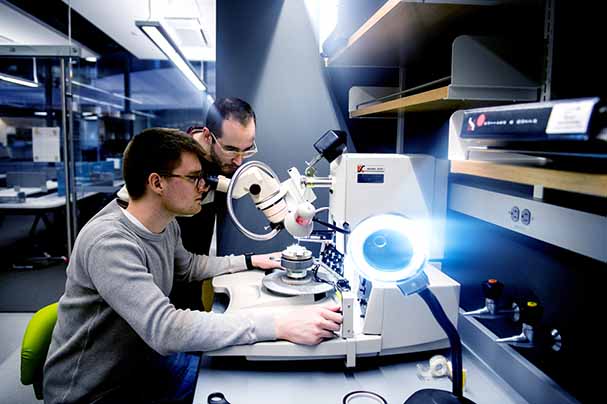 two students working in lab looking in microscope