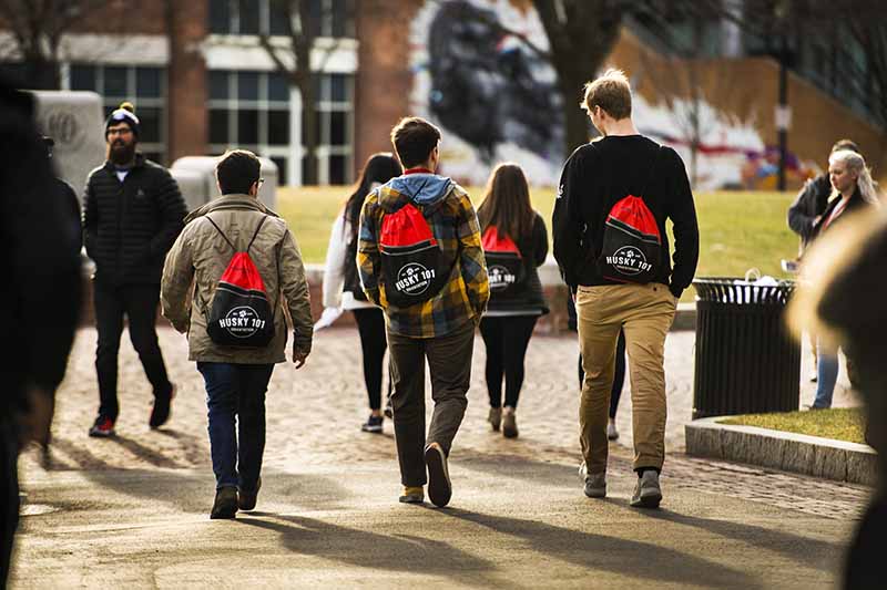 New students wearing their Husky 101 backpacks walk through Centennial Common