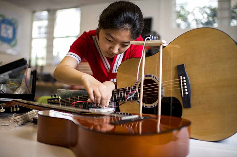Student works to adapt a guitar to enable a person to play a guitar with limited movement on one side of their body.