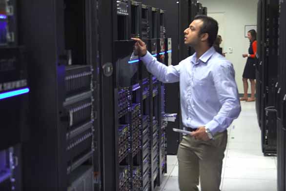 man working in data center pushing button on rack